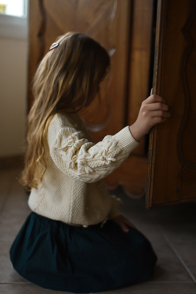 A girl in LRDM knitwear looking into a wooden wardrobe